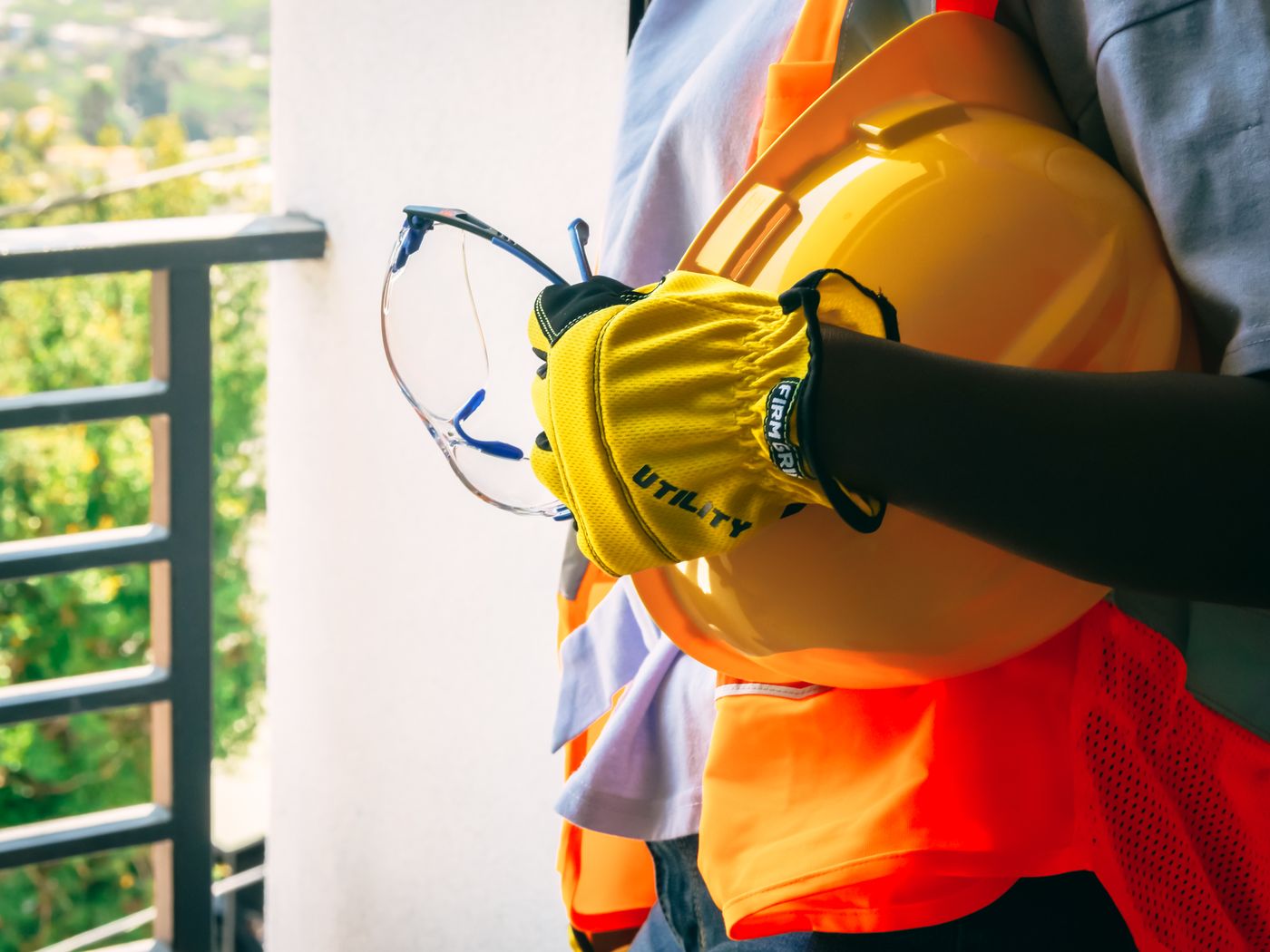 Close-up of gloved hands holding safety glasses and a yellow hard hat, accompanying the life insurance vs AD&D discussion of accident-related coverage limits.