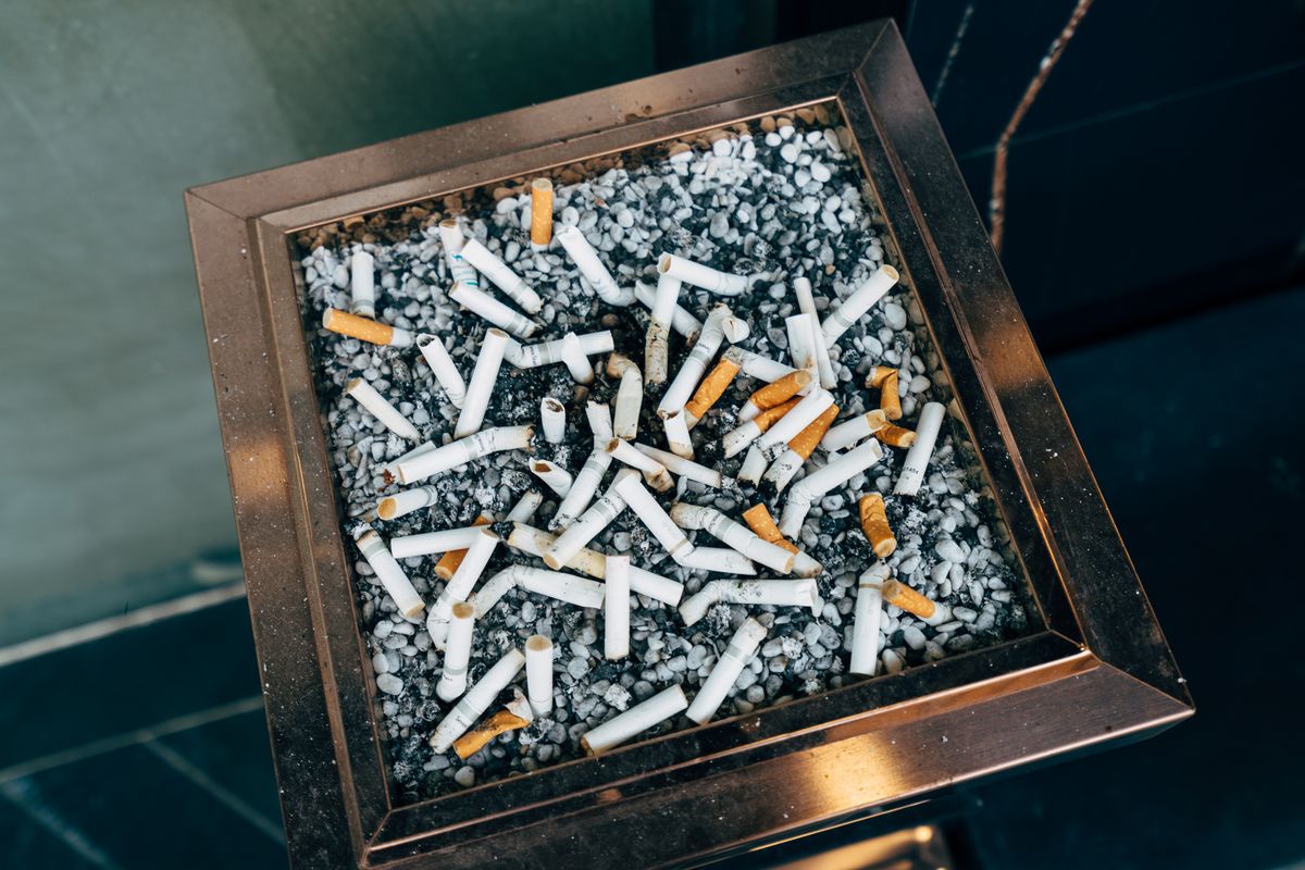Cigarette ends in a pebble-filled ashtray, illustrating tobacco-use history discussed when shopping for life insurance for smokers.
